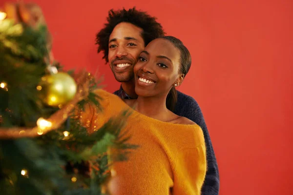 La pareja navideña perfecta. Foto de una pareja joven y cariñosa decorando su árbol de Navidad. —  Fotos de Stock