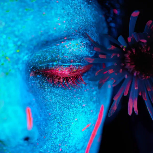 Beauté lumineuse. Tournage d'une jeune femme posant avec de la peinture au néon sur son visage. — Photo