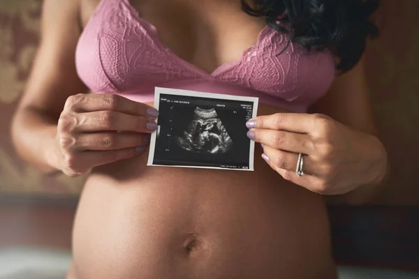 La prima foto del mio bambino. Colpo ritagliato di una donna incinta irriconoscibile in piedi nella sua camera da letto a casa. — Foto Stock