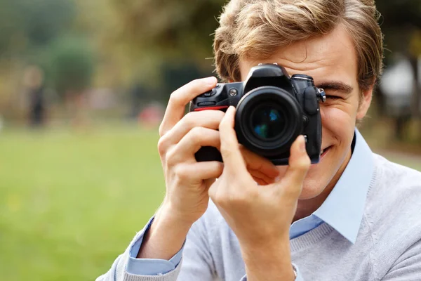 Encontrar o assunto perfeito. Tiro de um jovem tirando fotos em um parque. — Fotografia de Stock