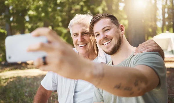 Sorridi. Ritagliato colpo di un bel giovane uomo e suo padre scattare selfie durante il campeggio nel bosco. — Foto Stock