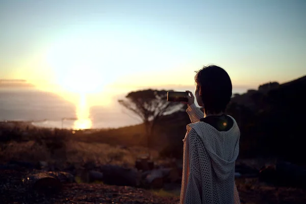 Jag måste bara fånga den här utsikten. Skjuten av en kvinna som tar bilder på sin mobiltelefon av solnedgången. — Stockfoto