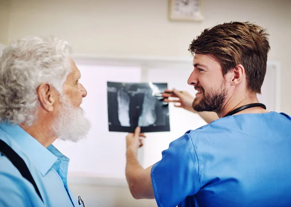 No hay nada de qué preocuparse. Fotografía de un joven doctor y su paciente mayor mirando una radiografía juntos. — Foto de Stock