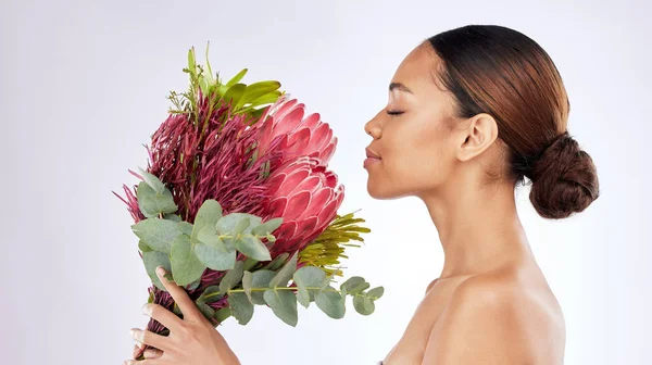 Pysähdy ja haista kukat. Kuvattu nuori nainen haistaa kukkakimpun studion taustaa vasten. — kuvapankkivalokuva