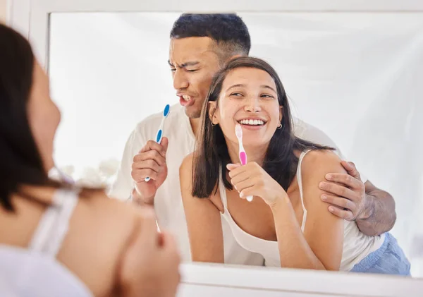 O, dişlerini fırçalamayı bir performans haline getirmek zorunda. Genç ve mutlu bir çiftin banyoda yan yana durup dişlerini fırçalarken neşeli hissetmeleri.. — Stok fotoğraf