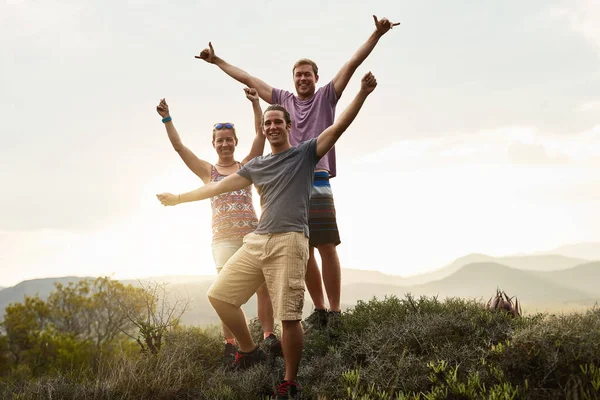 Vaeltakaa enemmän, huolehtikaa vähemmän. Muotokuva kolmesta onnellisesta ystävästä poseeraamassa yhdessä vaelluksen aikana vuorilla. — kuvapankkivalokuva