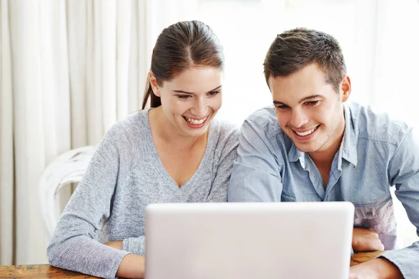 Söker på nätet tillsammans. Ett ungt par använder en bärbar dator tillsammans hemma. — Stockfoto