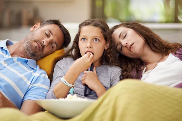 Serata film per famiglie. Girato di una ragazza seduta sul soggiorno a guardare un film con i suoi genitori addormentati accanto a lei. — Foto Stock