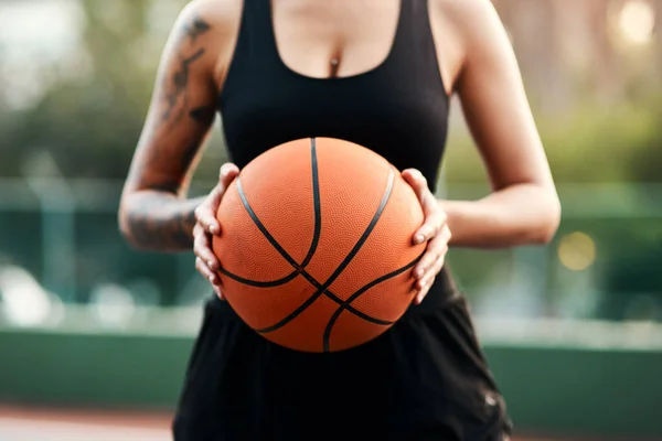 Empieza el juego. Recortado tiro de una deportista irreconocible de pie en la cancha solo y sosteniendo una pelota de baloncesto durante el día. — Foto de Stock