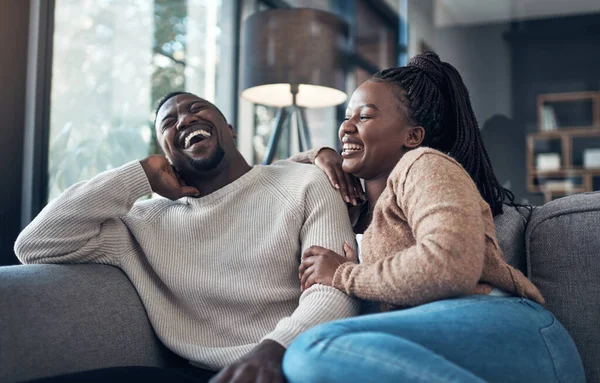 On ne passe jamais une journée sans rire. Plan recadré d'un jeune couple heureux assis ensemble et collant pendant leur week-end à la maison. — Photo