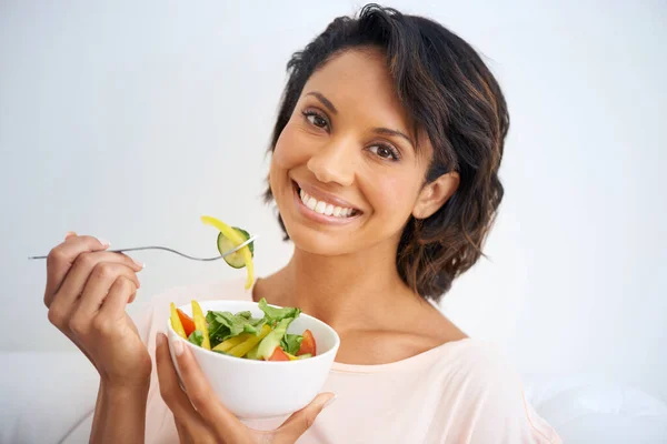 Feeling good starts with eating right. Portrait of a young woman enjoying a salad at home. — Stock Photo, Image