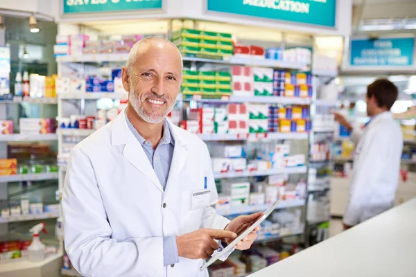 Segít, hogy naprakész maradjon a legfrissebb orvosi hírekkel. Egy érett gyógyszerész portréja digitális tablettát használva egy gyógyszertárban. — Stock Fotó