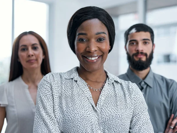 Сотрудничество высоко ценится в моей компании. Портрет деловой женщины, стоящей в офисе со своими коллегами на заднем плане. — стоковое фото