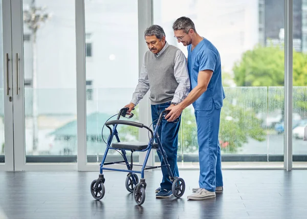 Förbättring av rörelsehinder ett steg i taget. Skjuten av en sköterska som hjälper en äldre man med en vandrare. — Stockfoto