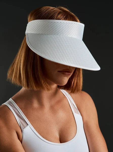 You wont see me on the court without my visor. Cropped shot of a sporty young woman wearing a sun visor against a dark background. — Stock Photo, Image