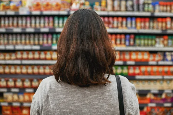 최고의 제품을 최고의 가격으로 찾는 거죠. 식료품 가게에서 물건을 찾고 있는 한 여자의 뒷모습. — 스톡 사진