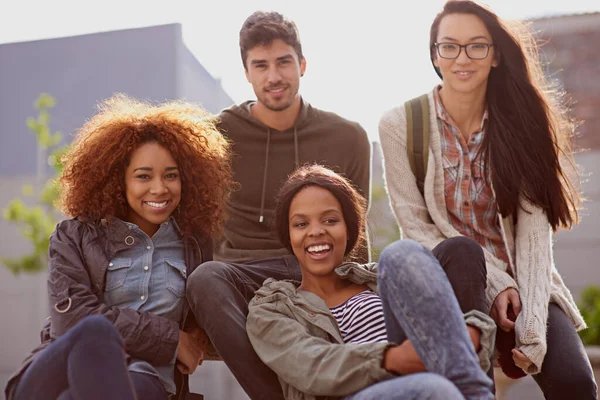 Making time for friends. Cropped shot of a group of students sitting outside while on campus. — Stock Photo, Image