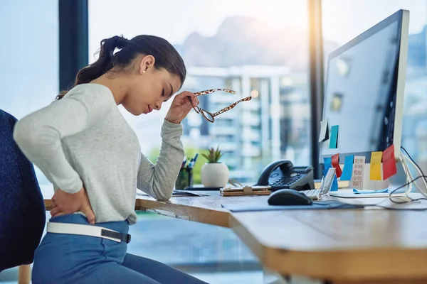 A tentar superar as dores de um dia difícil. Tiro de uma jovem empresária sofrendo de dor nas costas enquanto trabalhava em um escritório. — Fotografia de Stock