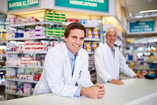 Az egyablakos gyógyszertárad az összes fontos egészségügyi dologért. Két gyógyszerész portréja, akik egy vegyésznél dolgoznak.. — Stock Fotó