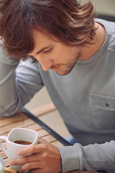 Denken Sie an den Tag, der vor uns liegt. Aufnahme eines jungen Mannes, der beim Kaffeetrinken nachdenklich wirkt. — Stockfoto