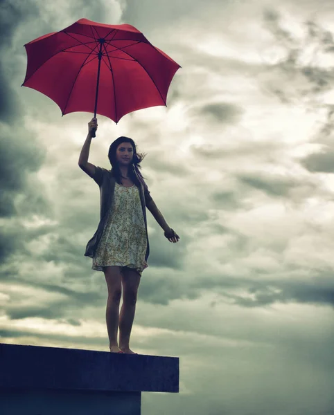 Kész szembenézni az élet viharaival. Aranyos fiatal nő kezében egy esernyő, miközben áll a tetőn. — Stock Fotó