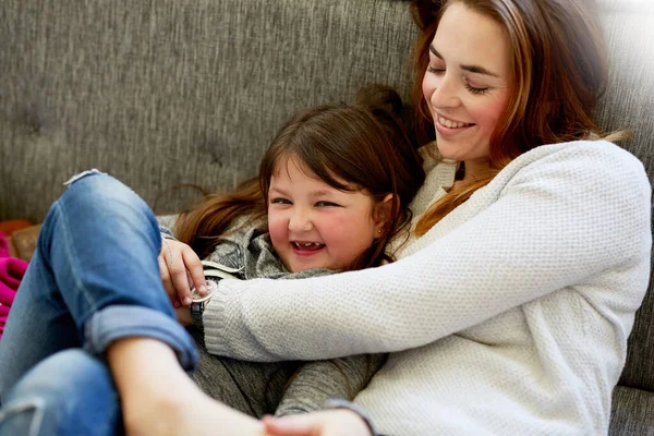 Coccole sul divano con la mamma. Girato di una madre che gioca con la sua bambina sul divano di casa. — Foto Stock