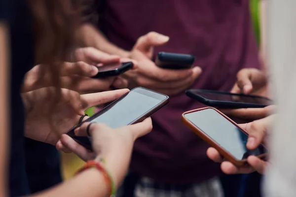 Vamos ver o que os outros amigos estão a fazer. Close-up de um grupo de jovens irreconhecíveis de pé em um círculo enquanto navega em seus telefones celulares fora durante o dia. — Fotografia de Stock