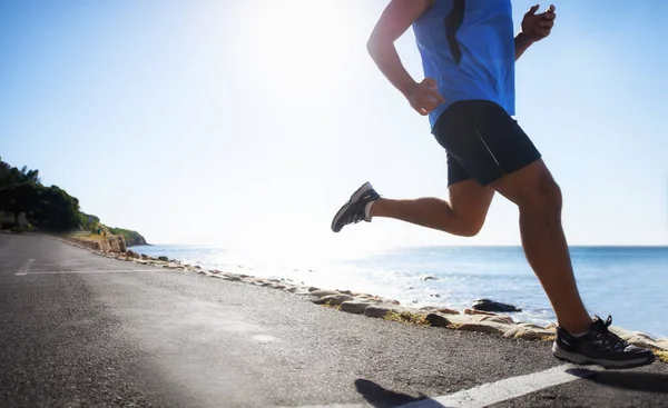 Running is a way of life. Low angle view of a runner next to the ocean. — Stock Photo, Image