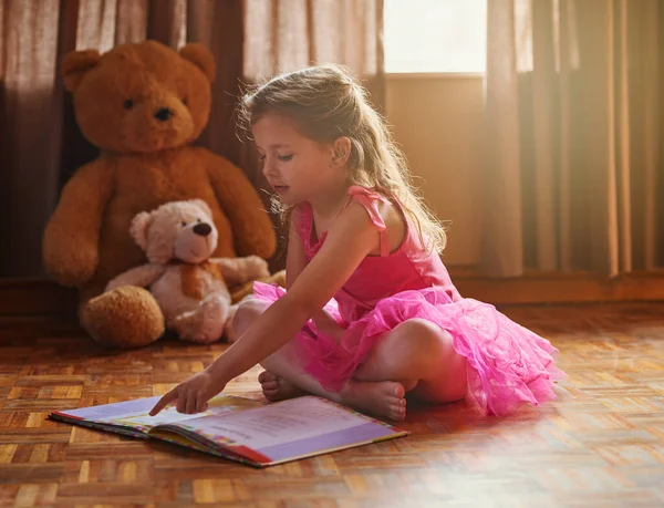 Учиться читать значит учиться видеть. Фотография маленькой девочки, читающей книгу рассказов. — стоковое фото