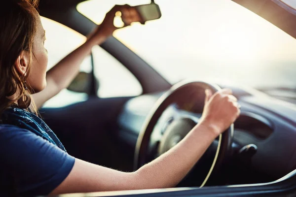 S'assurer qu'elle a une vue claire de son environnement. Plan recadré d'une jeune femme ajustant le rétroviseur dans sa voiture. — Photo