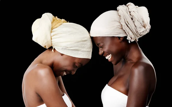 Leben, lieben und lachen. Studioaufnahme von zwei schönen Frauen mit Kopftüchern vor schwarzem Hintergrund. — Stockfoto
