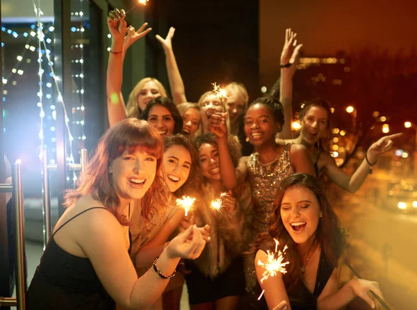Espumante para o Ano Novo. Tiro de um grupo de amigas que se divertem com faíscas em uma varanda em uma noite fora. — Fotografia de Stock