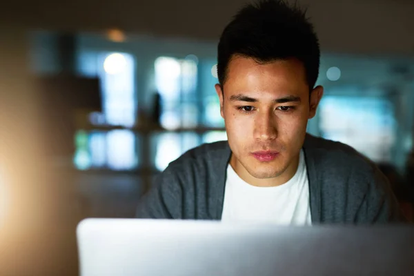 His job sometimes requires late nights. Shot of a handsome young male programmer working late in his office. — ストック写真