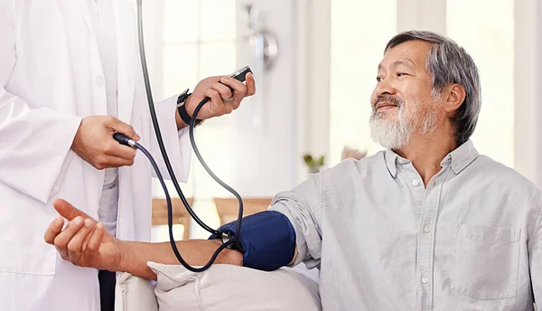 ¿Cómo estoy, doctor? Inyección de un médico masculino examinando a un paciente mayor con un medidor de presión arterial. —  Fotos de Stock