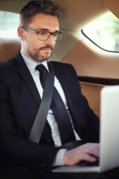 He starts working during his morning commute. Cropped shot of a businessman in the backseat of a car. — Stock Photo, Image