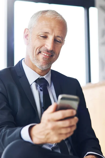 La interfaz en esto es increíble. Recorte de un hombre de negocios maduro mensajes de texto en un teléfono celular en una oficina. — Foto de Stock