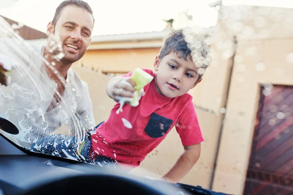 Este coche va a estar limpio y chirriante. Un disparo de una familia lavando su coche en la entrada. — Foto de Stock