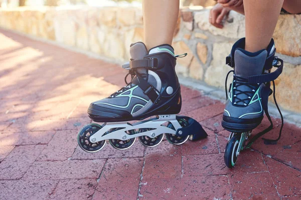 Es hora de que estas ruedas rueden. Primer plano de un joven pies de mujer en patines sentados en un banco del parque. —  Fotos de Stock