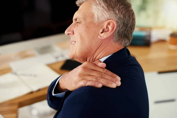 Luchando con un dolor de hombro insoportable. Recortado disparo de un hombre de negocios maduro que experimenta dolor de hombro mientras trabaja en una oficina. — Foto de Stock