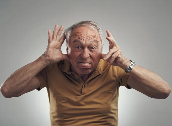 Int ouch met mijn innerlijke kind. Studio shot van een oudere man met een grappig gezicht tegen een grijze achtergrond. — Stockfoto