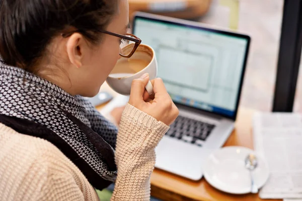 Sorseggiando caffè mentre godendo wifi gratuito. Foto ritagliata di una giovane donna attraente che naviga in rete in una caffetteria. — Foto Stock