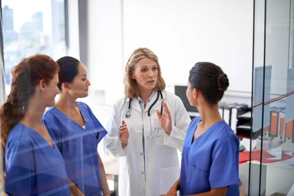 Giving them their instructions. Shot of a female doctor assigning tasks to a group of nurses at a hospital. — Stock Photo, Image