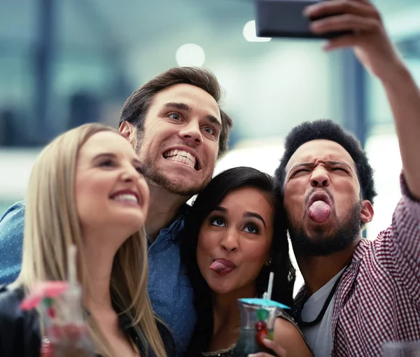 Faire des souvenirs ensemble. Tournage d'un heureux groupe d'amis prenant un selfie avec un smartphone dans une boîte de nuit. — Photo