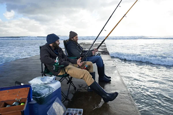 Pêche... c'est moins cher que la thérapie.. Tourné de deux jeunes hommes pêchant au large d'une jetée. — Photo