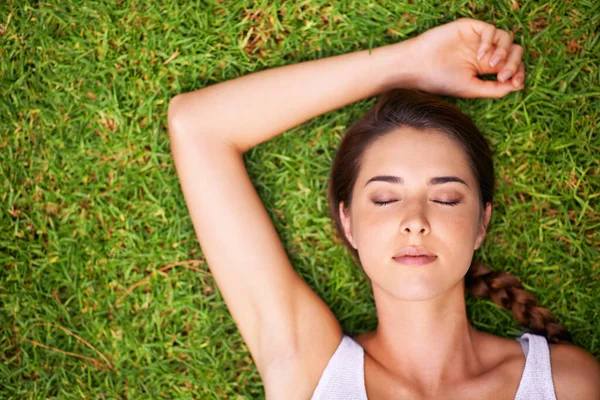 Enjoying some me time. A young woman lying on the grass outdoors.