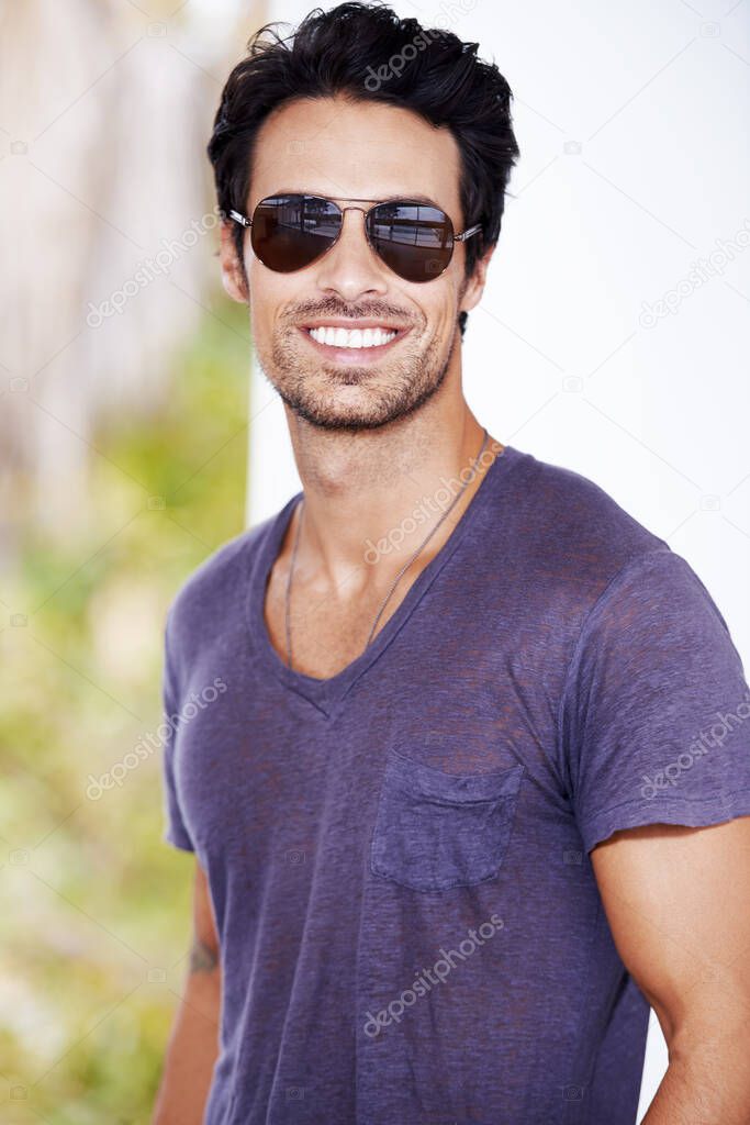 Looking stylish. Cropped view of a trendy young guy smiling while wearing shades.