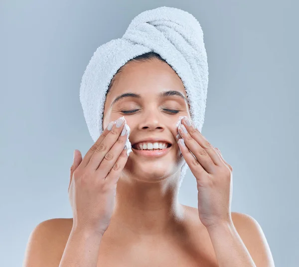Zorg dagelijks voor je huid. shot van een jonge vrouw wassen haar gezicht in de douche tegen een grijze achtergrond. — Stockfoto