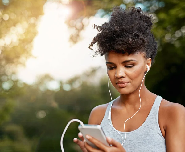A música é o que me motiva. Tiro de uma jovem mulher ouvindo música em seu telefone enquanto fora para uma corrida. — Fotografia de Stock