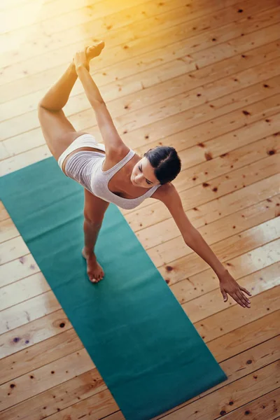 Perfeição o equilíbrio entre mente e corpo. Tiro de ângulo alto de uma jovem mulher fazendo ioga dentro de casa. — Fotografia de Stock