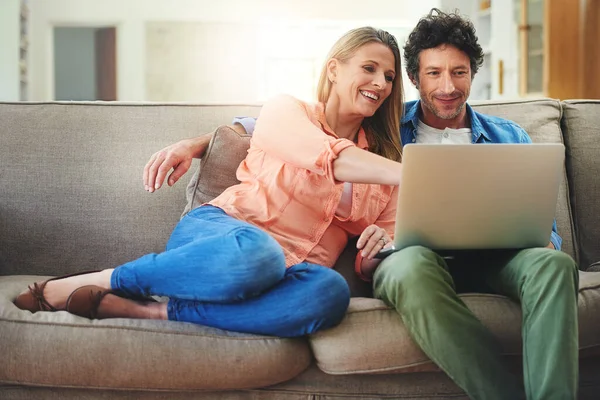 Soffa filmdejter är bäst. Skjuten av ett lyckligt moget par med en bärbar dator tillsammans på soffan hemma. — Stockfoto